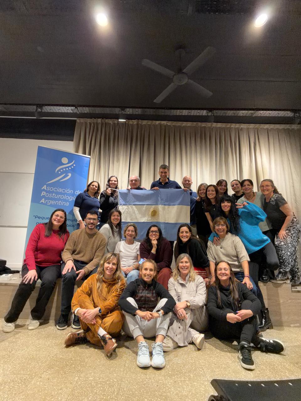 Comunidad profesional del Curso Anual de Posturología Clínica junto a la bandera argentina